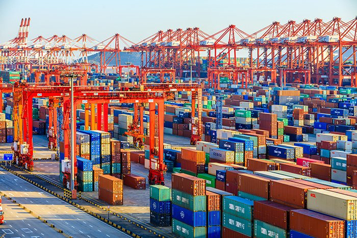 European container market represented by a busy container terminal with stacked boxes and gantry cranes